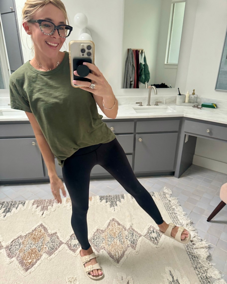 woman taking selfie in mirror wearing black leggings and green tshirt