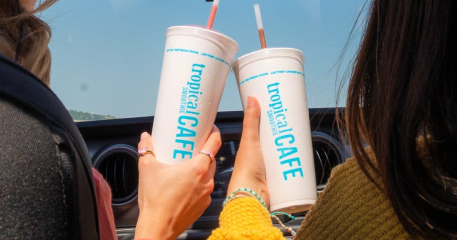 Women holding Styrofoam tropical smoothie café cups inside car