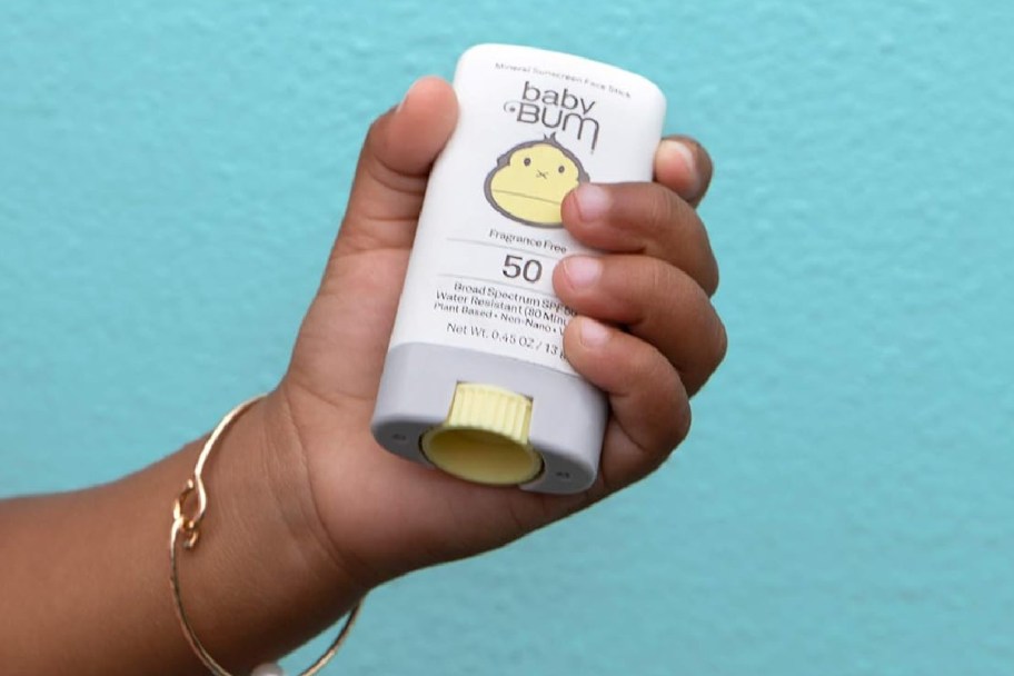 baby hand holding sunscreen stick