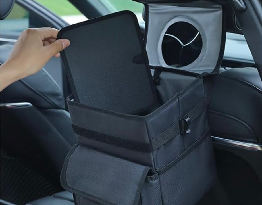 person showing car trash can mat in back of car