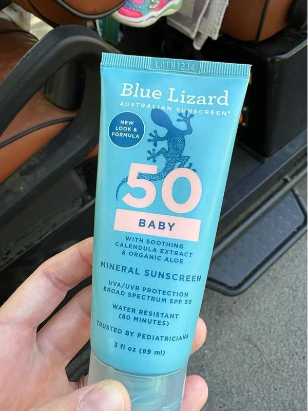 hand holding a tube of blue lizard baby sunscreen