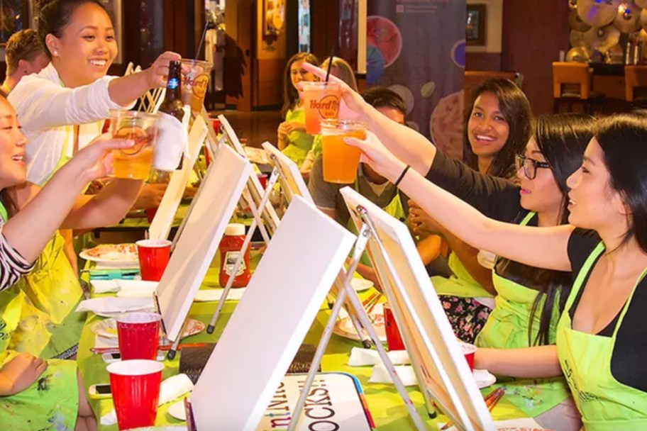 people raising glasses at paint and sip night