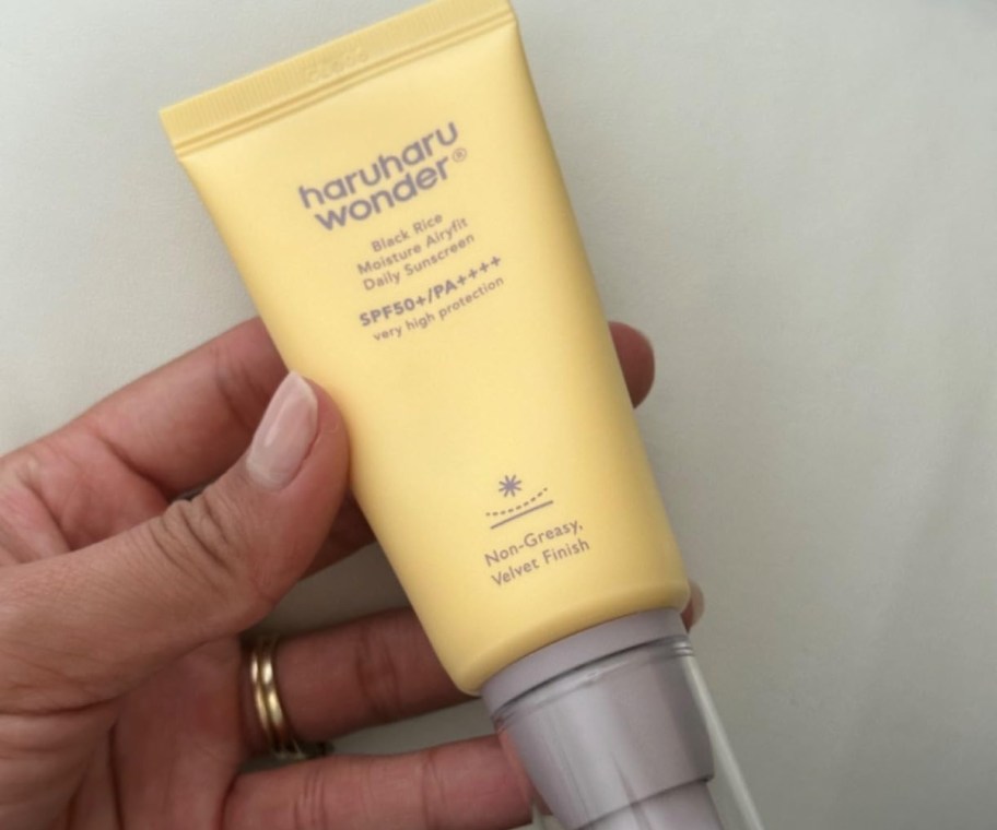 hand holding korean sunscreen in yellow tube
