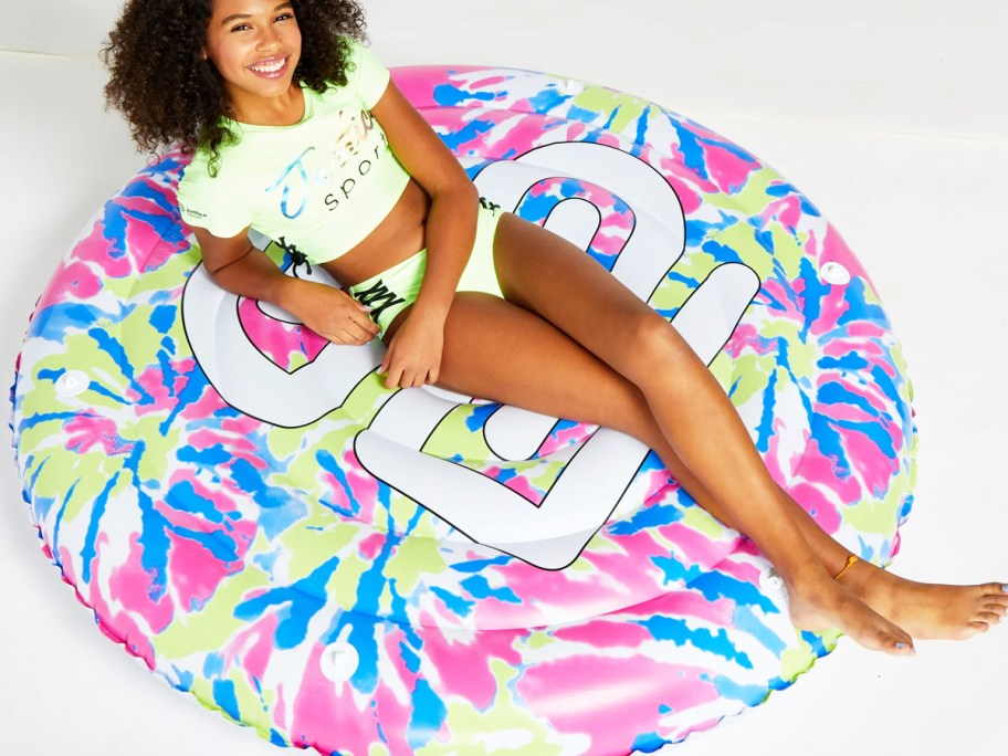 girl laying on a tie dye pool float