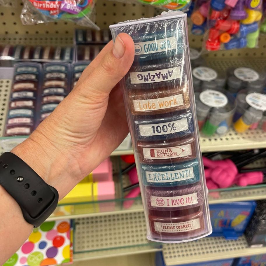 a womans hand holding a pack of teacher stamps