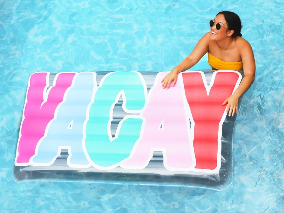 woman in pool next to a float that says vacay