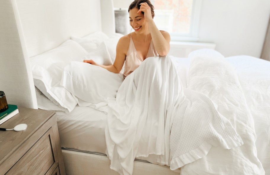woman sitting on bed with white sheets