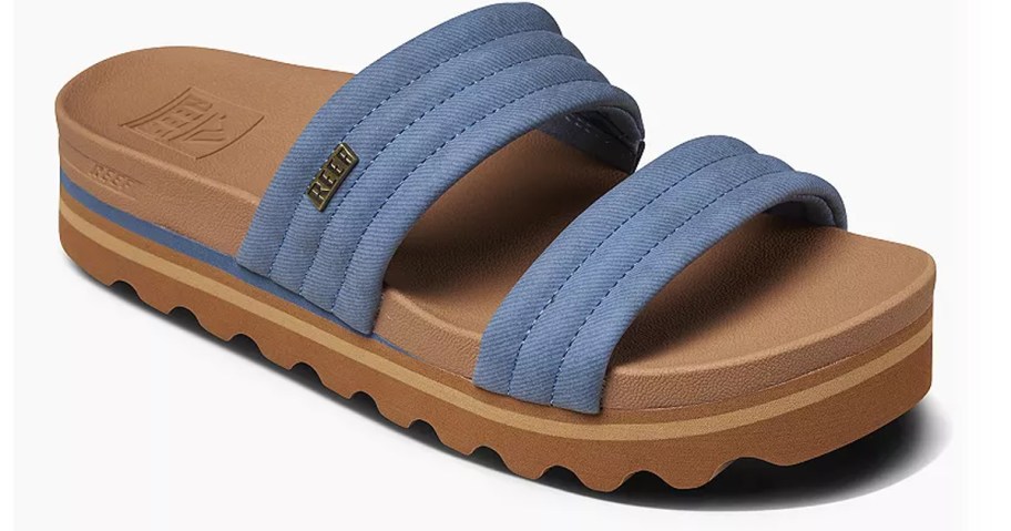A REEF Kaia women's sandal with two wide, padded blue straps and a thick brown platform sole with a textured bottom for grip.