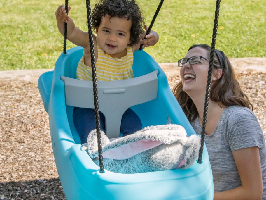 toddler and a plush rabbit in a Step2 Swing with a woman off to the side looking on