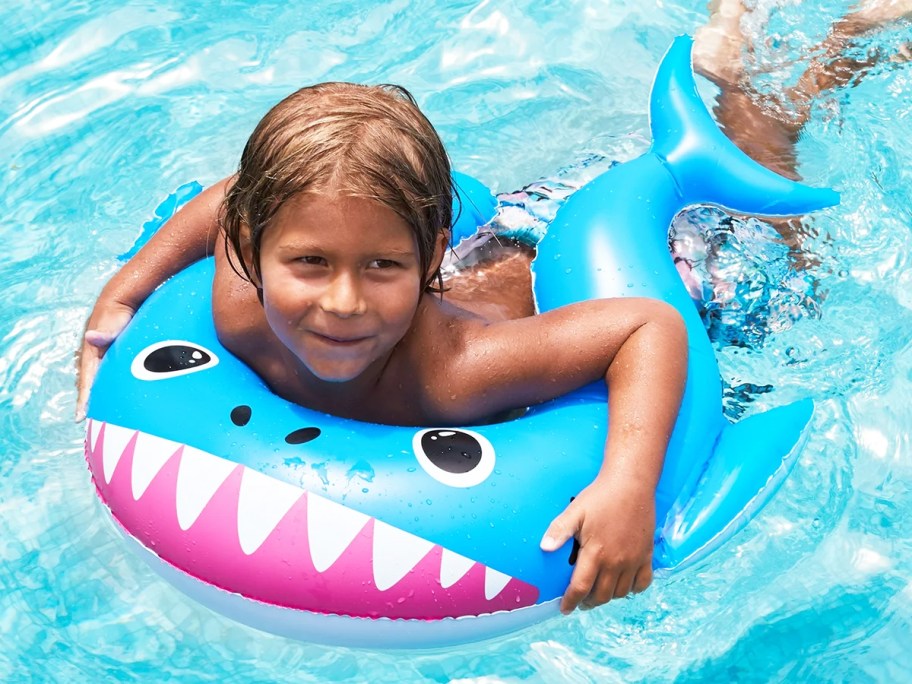 boy on a blue shark pool float