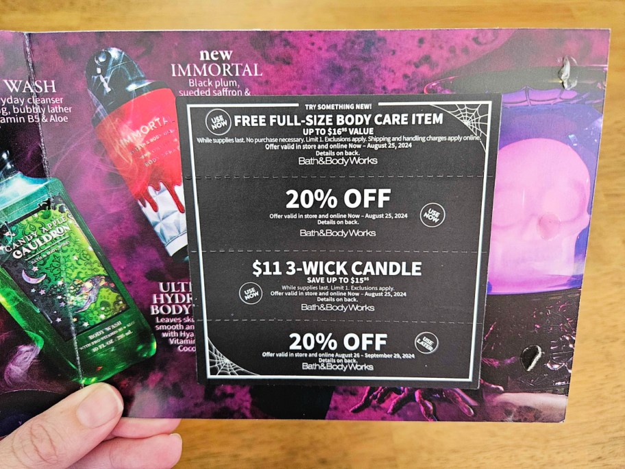 hand holding the halloween bath and body mailer coupons close up