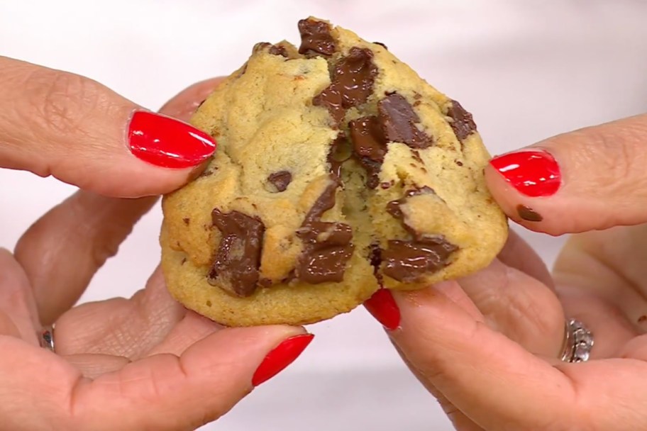 hands breaking chocolate chip cookies in half