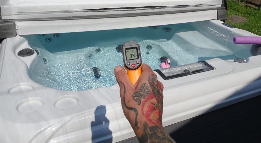 hand holding thermal thermometer over hot tub
