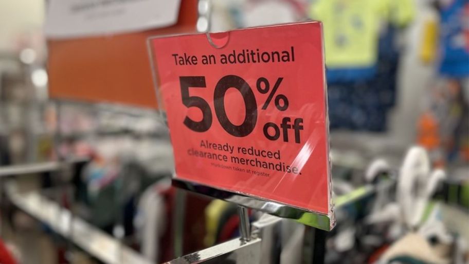 a red sign on top of a clothing rack in a Kohl's store - the sign says Take an additional 50% off clearance