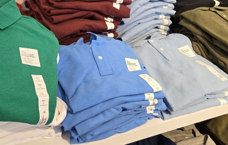 stacks of folded mens polo shirts on a display table in a store