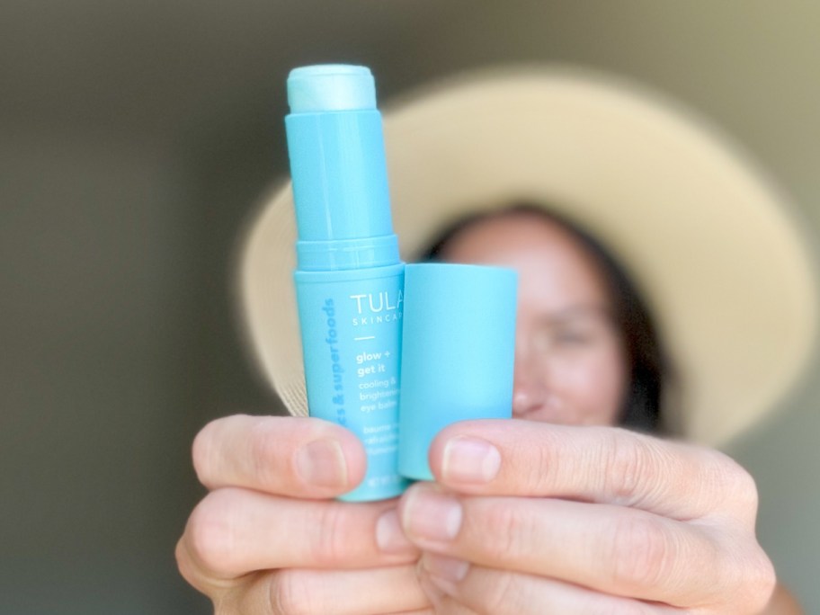 woman holding eye balm in front of face