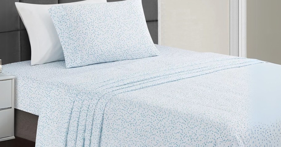 a twin bed with a blue and white sheet set and pillows on it