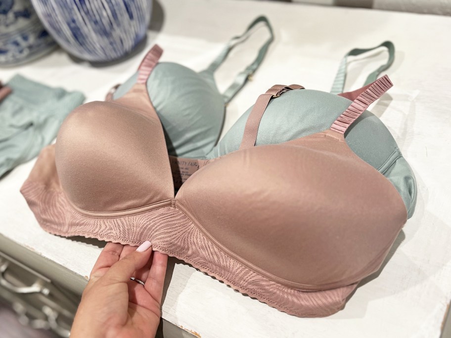 hand touching blush colored bra on top of dresser