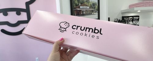 a womans hand holding a pink crumble cookie box