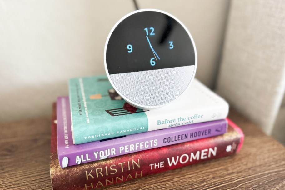 round smart device alarm clock on stack of books