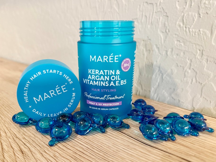 maree hair oil jar with capsules laying beside it 