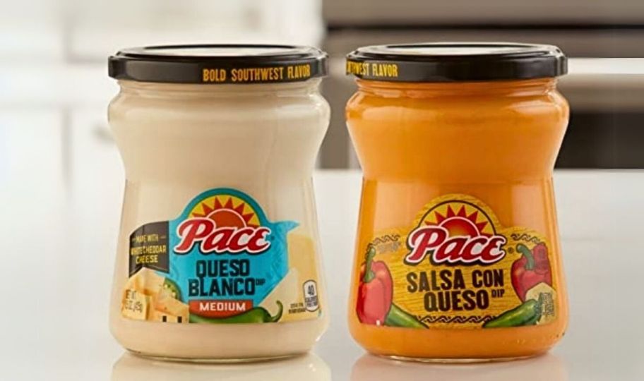 a jar of queso blanco and a jar of salsa con queso on a kitchen counter