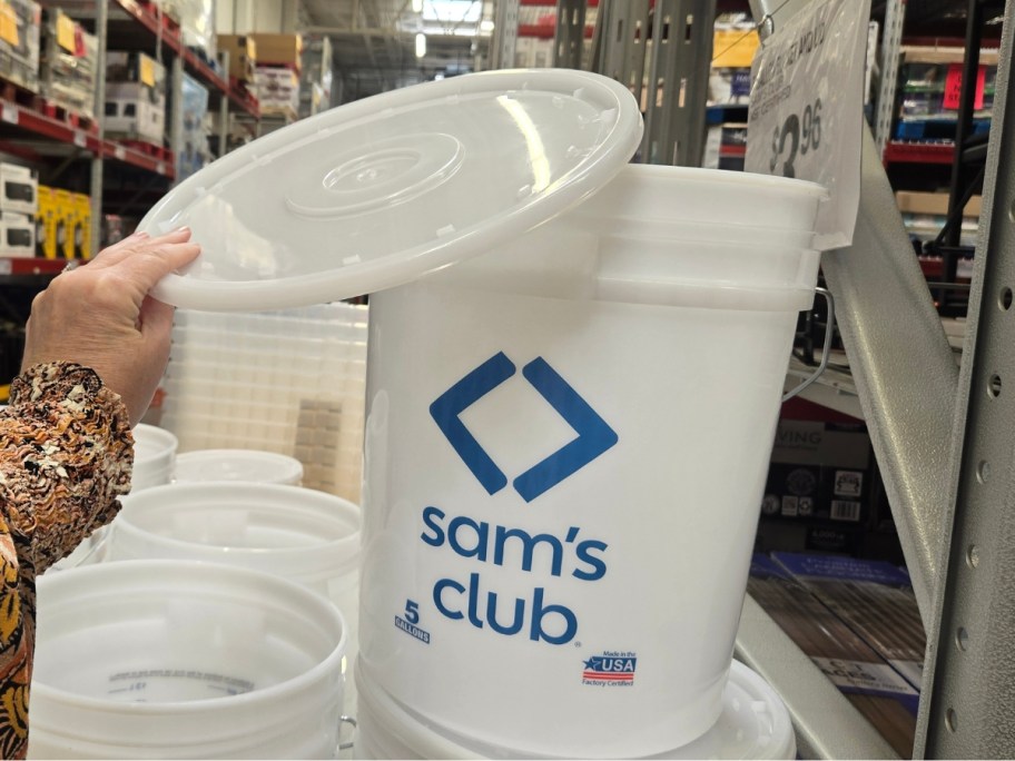 hand holding a lid up to a large 5 gallon Sam's Club bucket in a store aisle