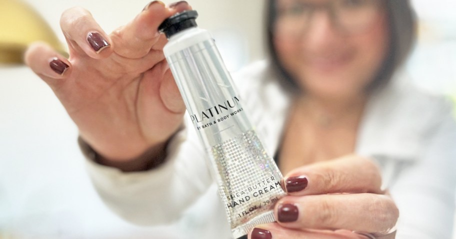 woman holding up a tube of Bath & Body Works Hand Cream