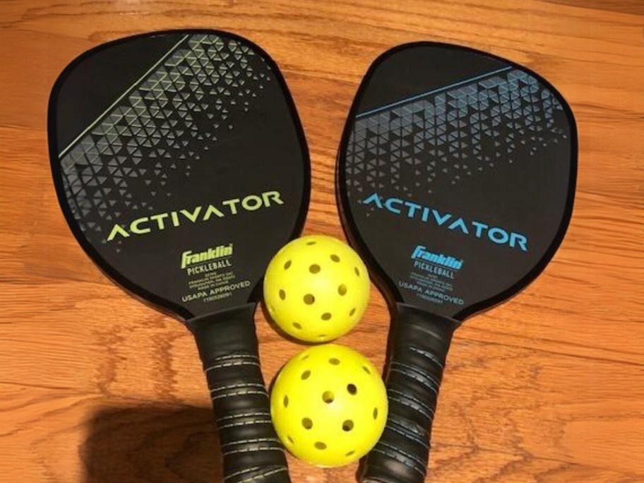 2 pickleball paddles and 2 balls on wood table