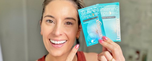 woman holding up and pointing to a set of Lumineux Teeth Whitening Strips
