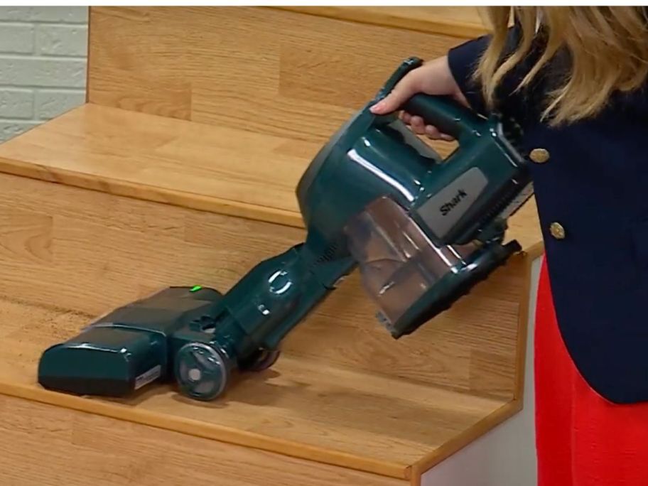 Woman using a Shark Stick vacuum to clean stairs
