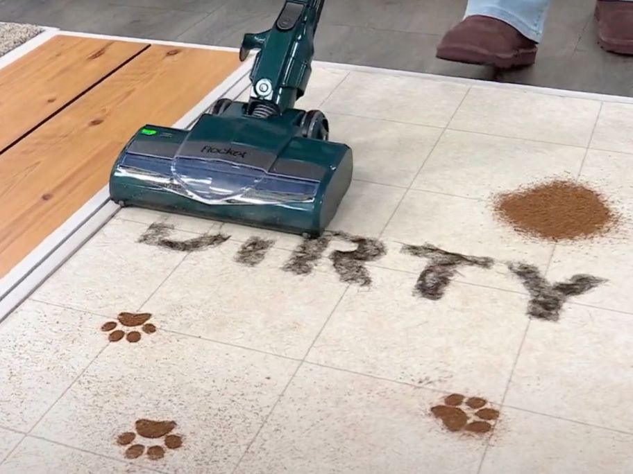 A shark stick vacuum cleaning dirt off a carpet