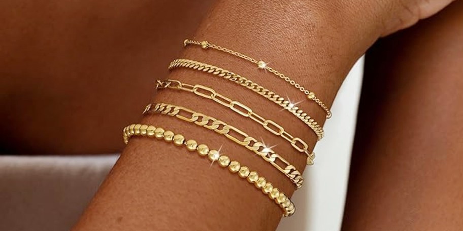 wrist with 5 gold bracelets on it 