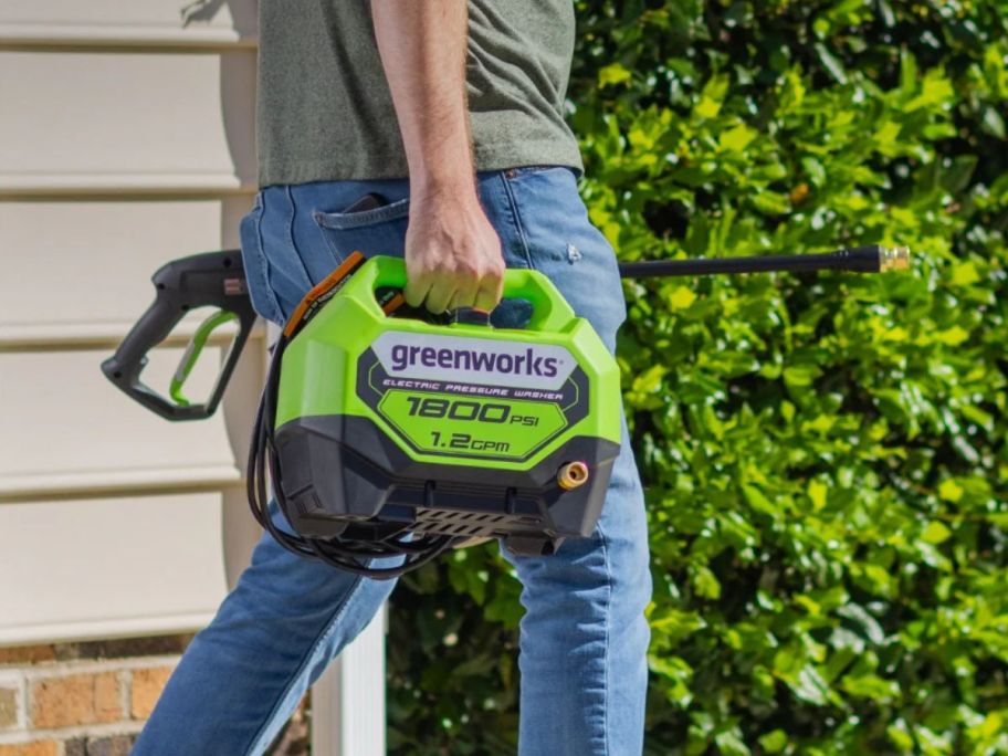 person carrying Greenworks 1800 PSI Cold Water Electric Pressure Washer w/ 2 Spray Tips outside