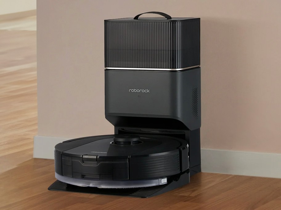black robot vacuum sitting in dock against wall