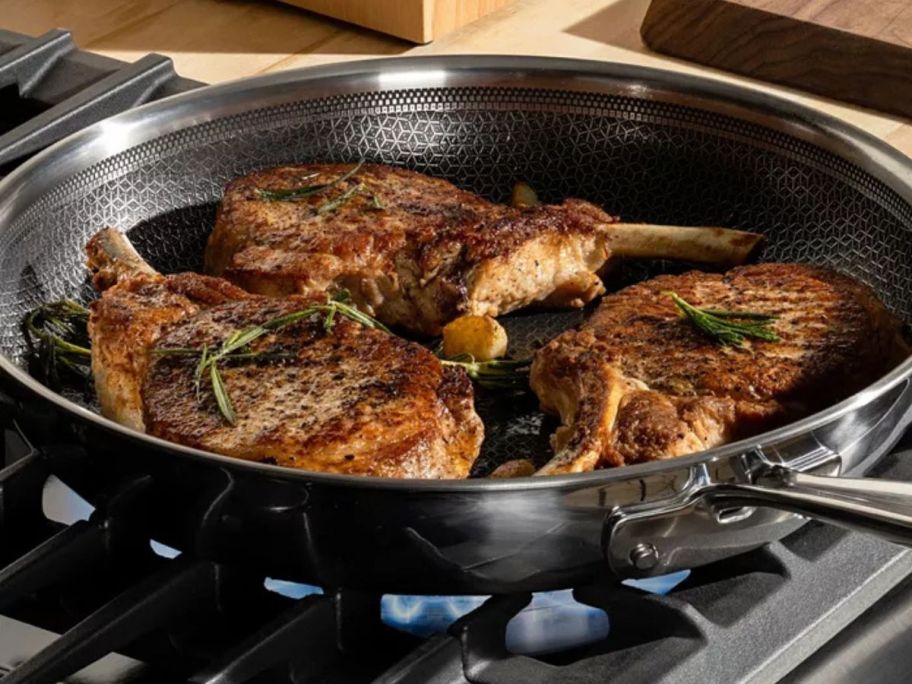 T-Fal Hybrid Mesh Stainless Steel 10.5" Frypan on stove with meat in it