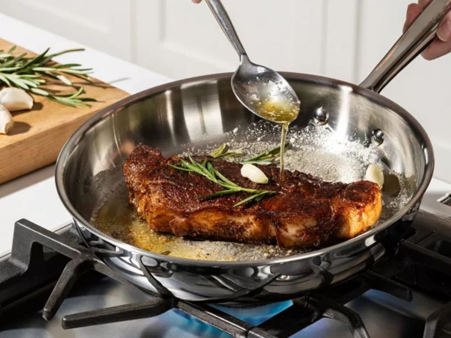 T-Fal Pro Tri-Ply Stainless Steel 10.5 " Frypan on stove with meat in it