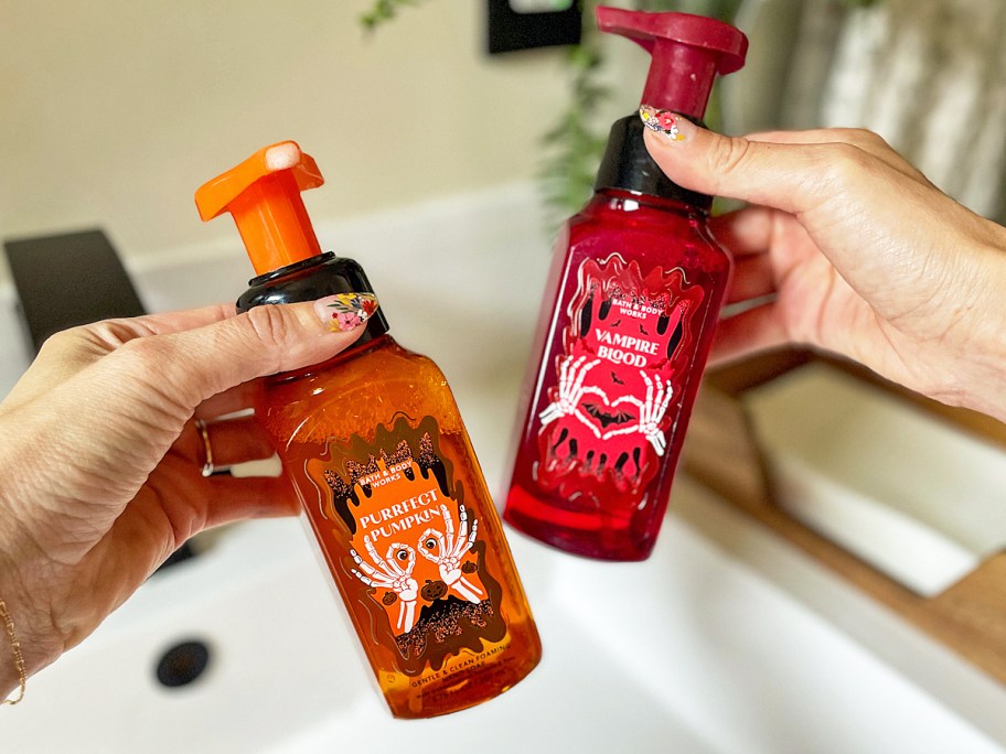hands holding up orange and red bottles of Bath & Body Works Halloween Hand Soaps