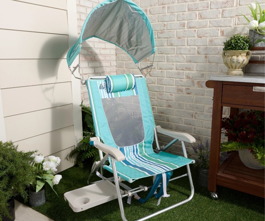 gci beach chair with adjustable shade, armrests, and side table in backyard