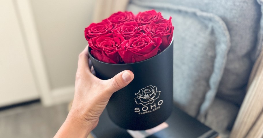 hand holding up a black box full of red roses