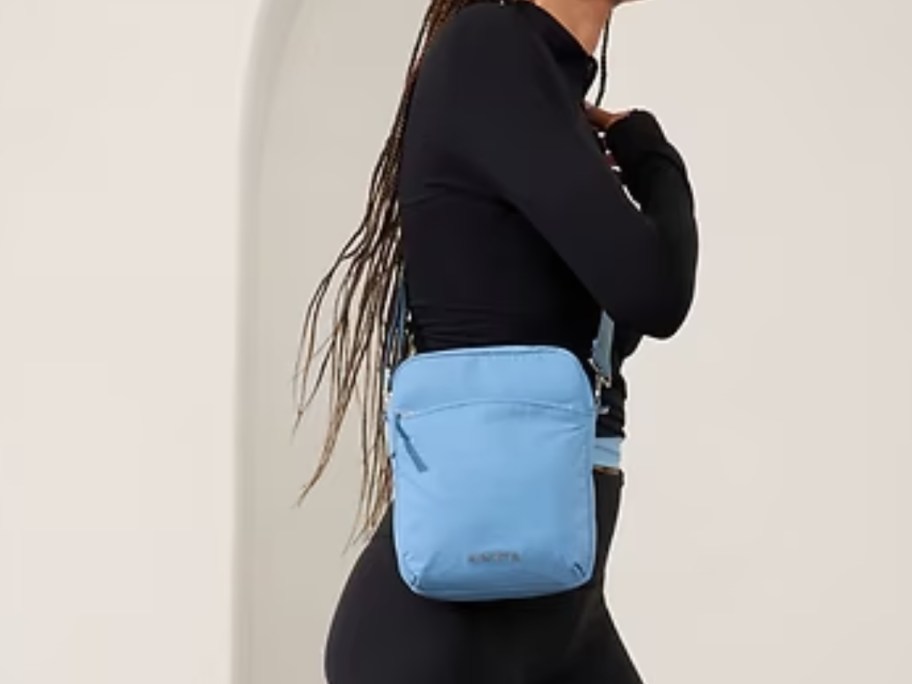 woman wearing a black jacket and pants with a light blue crossbody bag