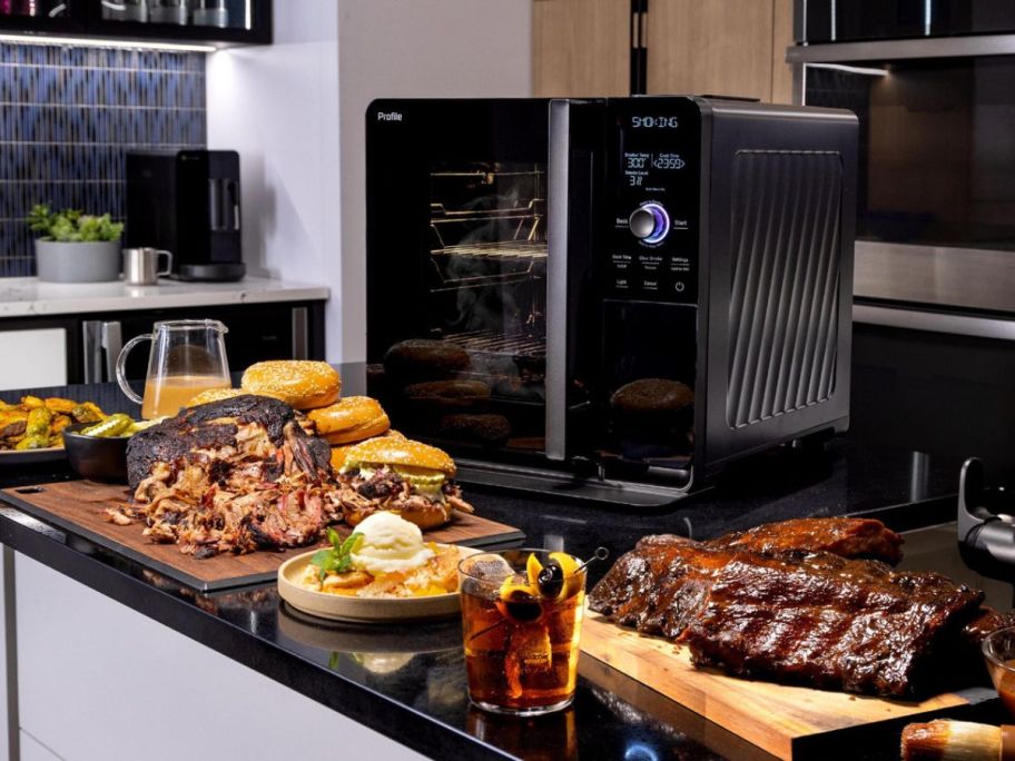 GE Profile Smart Indoor Pellet Smokers surrounded by plates of smoked meats