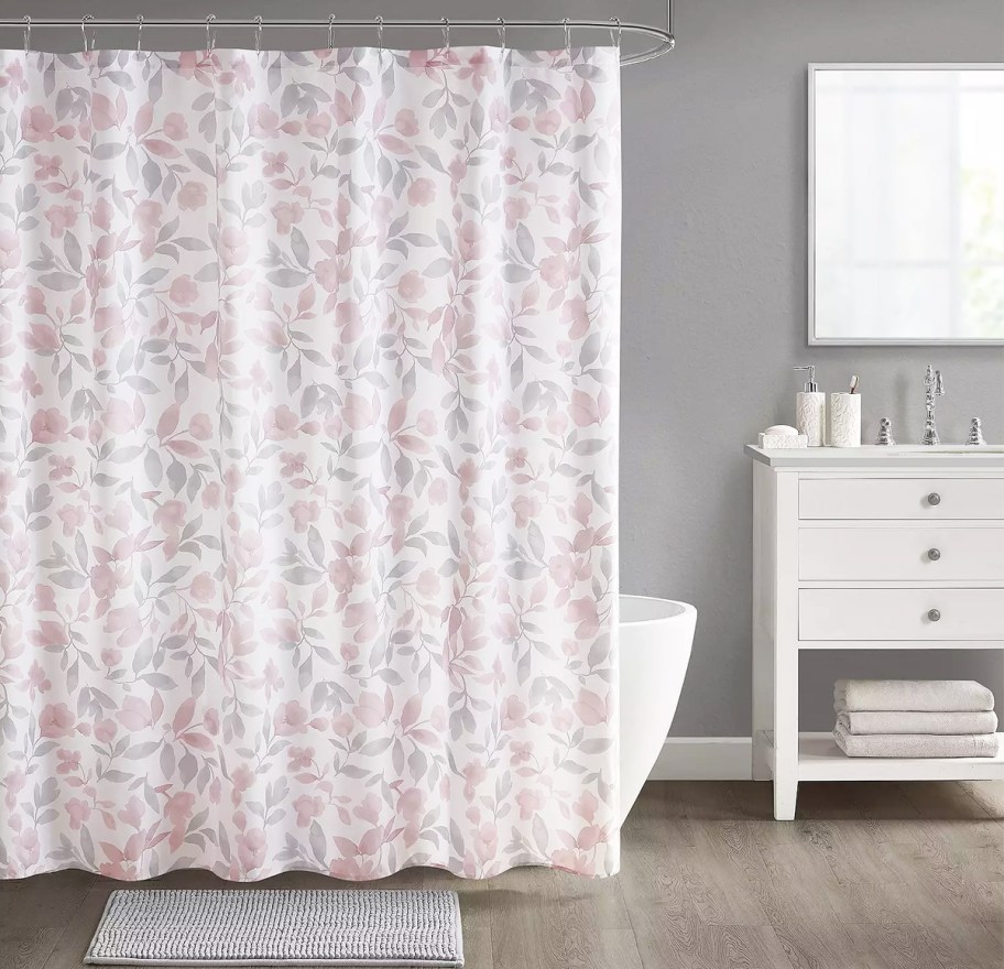 bathroom with a floral print shower curtain, coordinating bath rug, and vanity with lotion and soap pumps