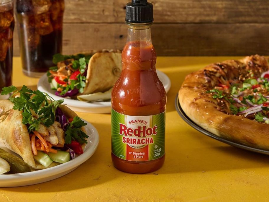 Frank's RedHot Sriracha Chili Sauce 12oz Bottle with tacos and pizza around it