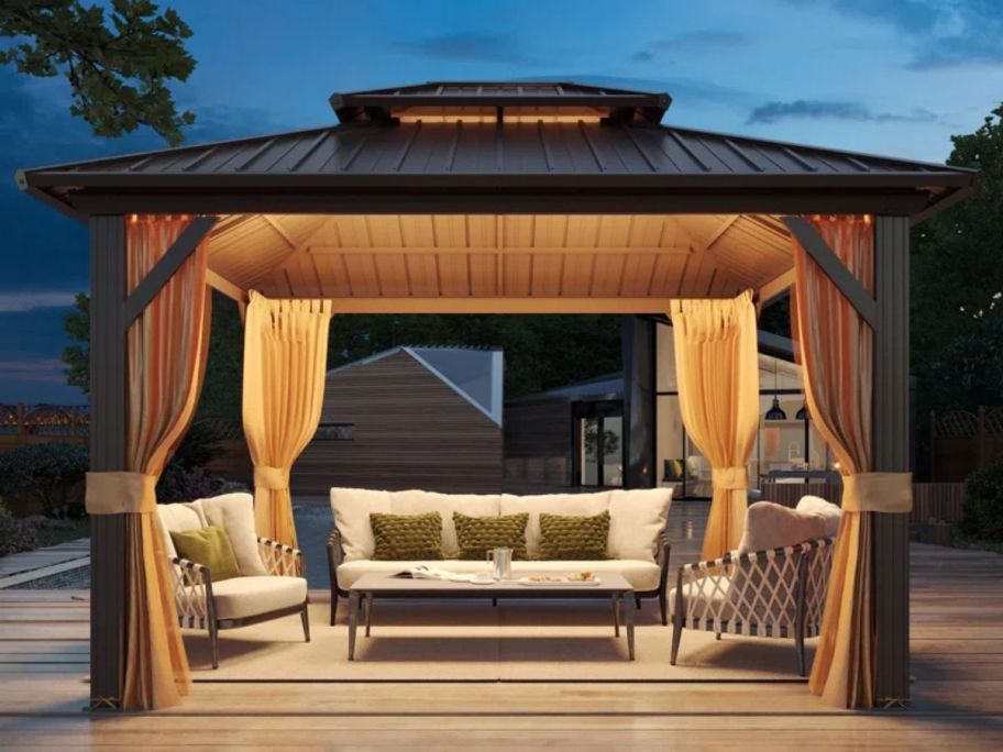 brown gazebo with patio set underneath at night