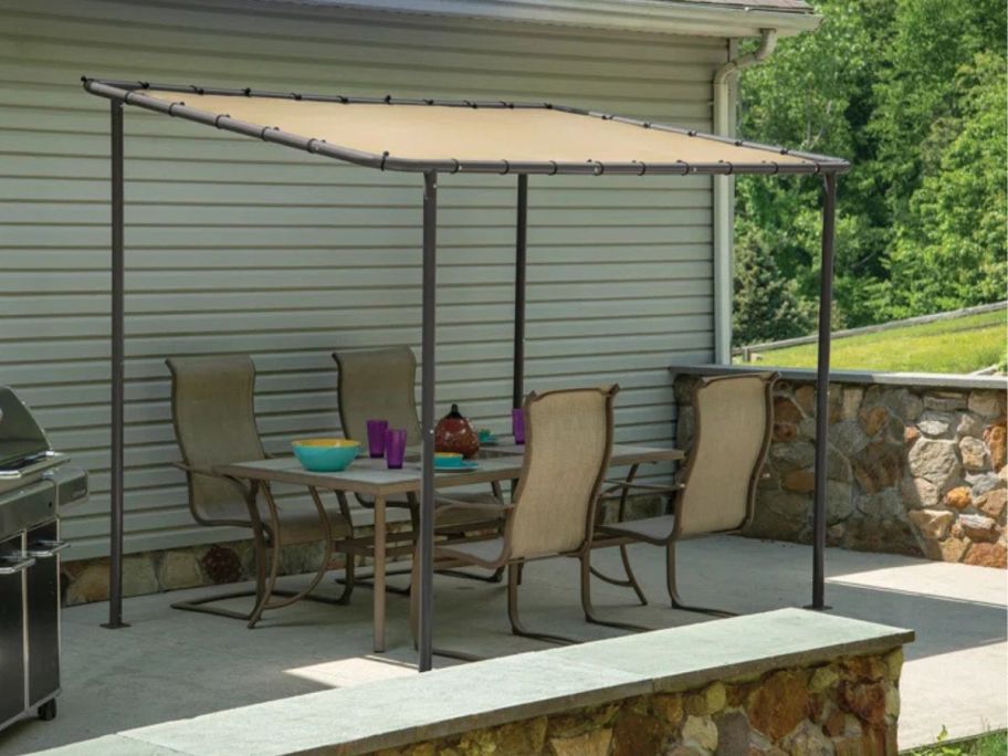 beige gazebo on patio with patio dining set underneath