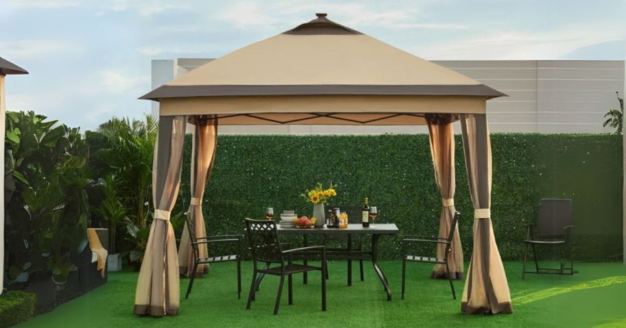 beige and brown gazebo with patio dining set underneath in the grass