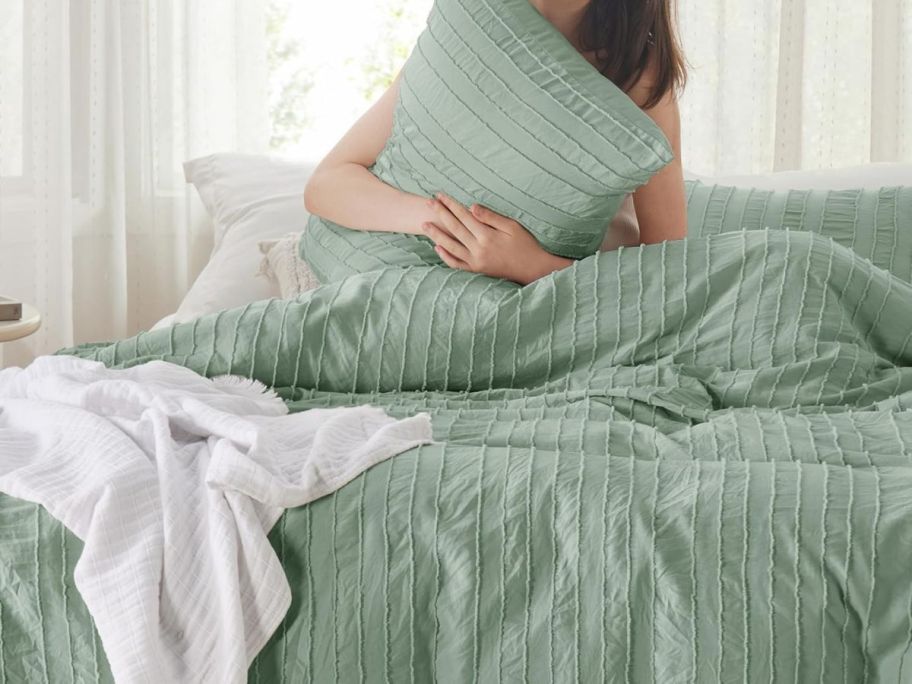 A woman in bed with a striped light green duvet and pillow set