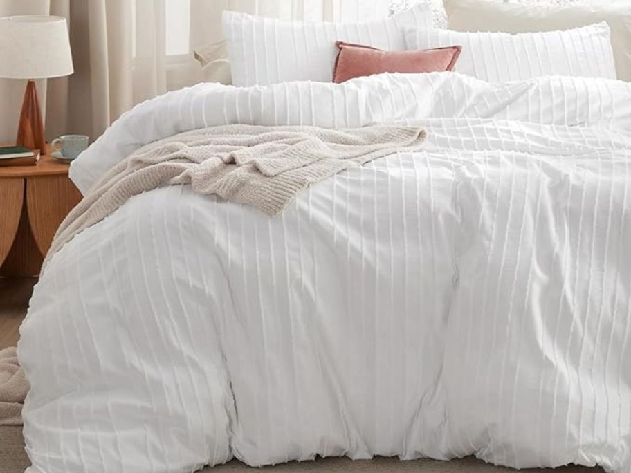 A bed with a white duvet covering it 