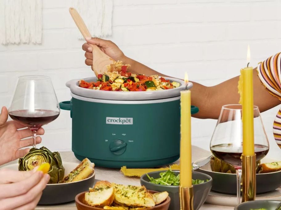 person stirring food inside of Crock-Pot 4.5-Quart Slow Cooker in kitchen